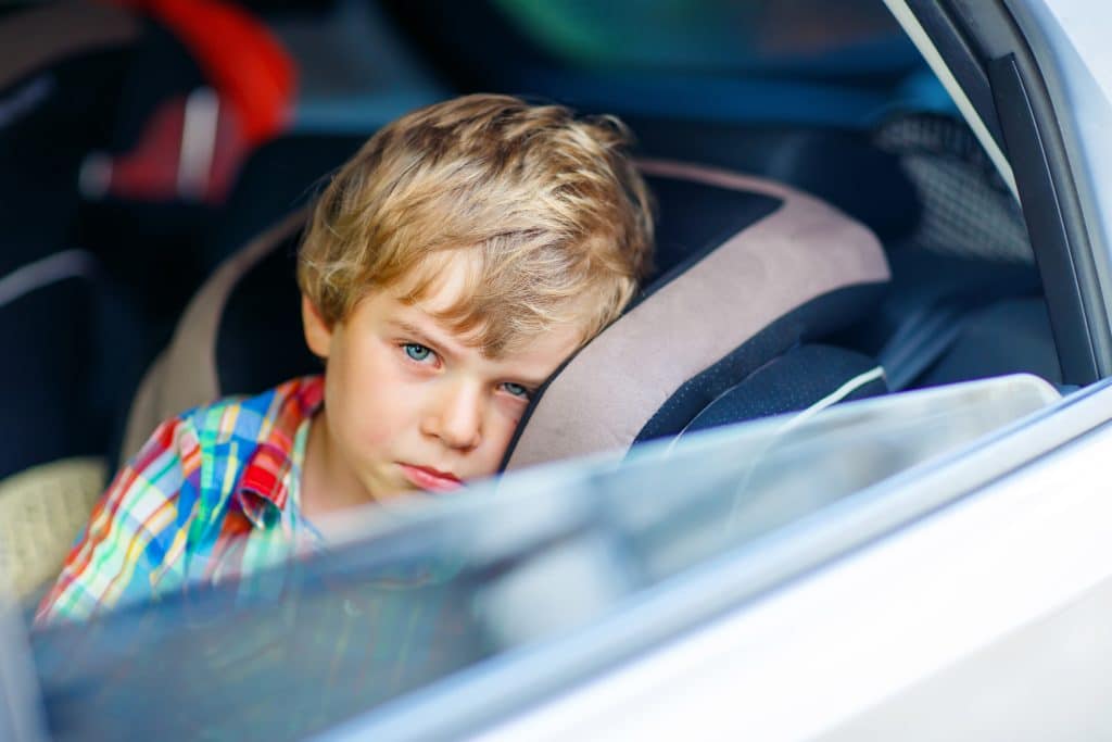 Ein trauriger Junge der aus dem Autofenster schaut weil er in einem Wechselmodell sein muss